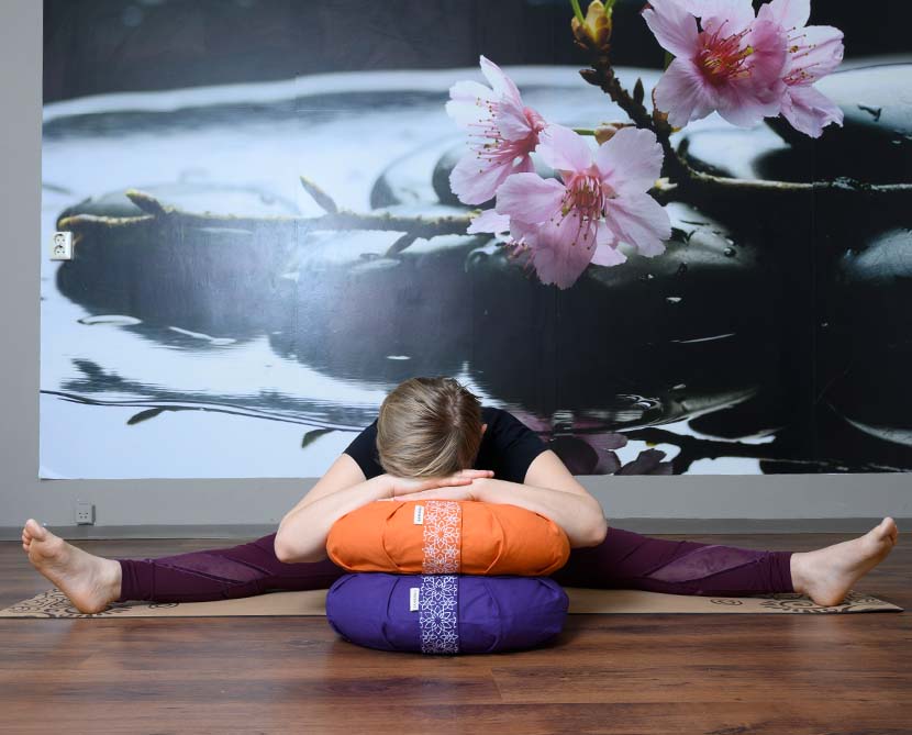 A female relaxing on crescent meditation cushions and sitting on cork yoga mat