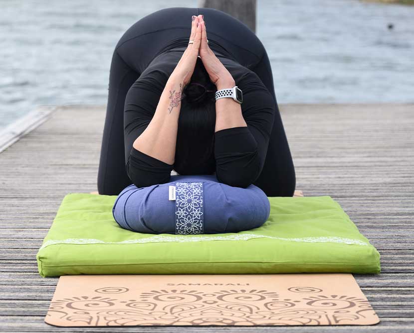 A female exercising in the park using Zafu meditation cushion, meditation mat and cork yoga mat