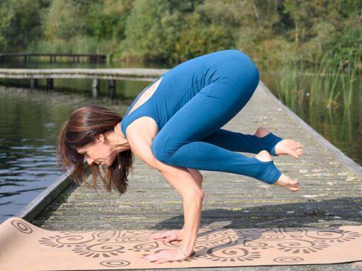 A female in the blue jumpsuit doing arm balances on the cork yoga mat 